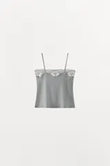 Top de punto fino con textura acanalada, escote recto y tirantes finos ajustables. Presenta una delicada aplicación de encaje a tono en el borde superior.