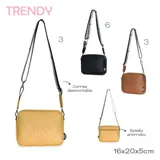 Bandolera pequeña de forma cuadrada, color marrón claro, con textura de cuero sintético. Presenta un logo circular grabado en el frente. La correa es ancha, de tela blanca y negra con la palabra "TRENDY" repetida.