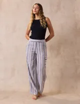 Pantalón de lino con rayas verticales en tonos beige, azul y gris. Tiene pretina elastizada, bolsillos inclinados en la parte delantera y un bolsillo tipo cargo en el lateral. Marca Zac & Rachel.