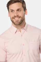 Camisa lisa de manga corta color crema, confeccionada en 100% algodón, con cuello abotonado y un bolsillo en el pecho.