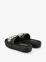 Sandalias tipo plataforma con base de acabado trenzado y capellada ancha decorada con apliques de diseño floral.