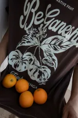 Remera blanca oversize de algodón con estampado de frutas y texto en el frente, pespuntes a contratono y tajos laterales.