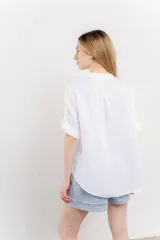 Camisa color topo confeccionada en lino, de corte holgado, con escote en V abotonado, bolsillo frontal y mangas 3/4 arremangables.