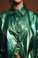 Camisa verde metalizada de corte holgado, con cuello clásico, cierre frontal con botones y mangas largas.