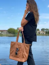 Bolso tote de cuero color marrón con doble asa de hombro y bolsillo externo con cierre.