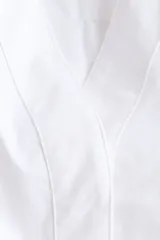 Blusa de algodón H&M Edition blanca con maxiescote en V, botones ocultos y canesú en la espalda. Presenta hombros caídos, mangas largas con puños abotonados y pinzas pronunciadas en la cintura que definen una silueta estructurada, con bajo asimétrico más largo en la espalda.