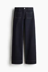 Jean de denim azul oscuro con tiro alto y corte wide leg de pierna amplia. Presenta bolsillos delanteros tipo parche con costuras pespuntadas en contraste y cierre frontal con botón y cremallera.