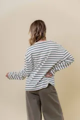 Remera de manga larga con diseño de rayas horizontales verdes sobre fondo crudo, cuello redondo con detalle de volado y cartera frontal con botones.