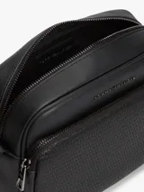 Bandolera Tommy Hilfiger de color negro, confeccionada en poliuretano con diseño de compartimento principal con cierre de cremallera y bolsillo exterior frontal con panel de textura tejida. Cuenta con correa ajustable, bolsillo interior con cierre y detalles distintivos de la marca con logo metálico en la parte delantera.