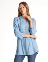 Blusa de lyocell color azul claro, con cuello camisero, escote en V y cierre frontal parcial con botones. Presenta mangas tres cuartos amplias y un corte holgado con aberturas laterales en el ruedo.