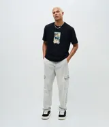 Pantalón de jean corte baggy con bolsillos cargo laterales, cierre de botón y cremallera, y cintura con trabillas.