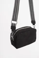 Bandolera negra de gamuza sintética con correa ancha de tela con diseño geométrico en blanco y negro.