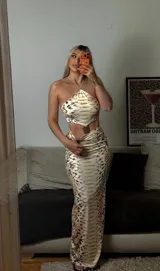 Vestido midi de dos piezas con estampado de piel de serpiente, compuesto por un top tipo halter con detalle metálico frontal y una falda ajustada de tiro alto.