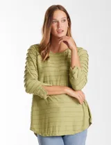 Blusa de silueta fluida en tejido shaggy con textura de franjas horizontales. Presenta cuello a la base, mangas tres cuartos con tajo lateral en el puño y ruedo redondeado con corte asimétrico, siendo más largo en la parte posterior.