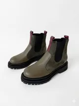 Botas tipo chelsea de cuero, combinando texturas en color bordó. Presentan paneles laterales elásticos en negro, suela track robusta y tiradores en la parte superior.