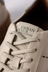 Championes urbanos de cuero en color crema con suela de goma gruesa en tono caramelo. Presentan detalles de costuras decorativas en el lateral y un refuerzo en el talón en color gris.