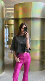 Pantalón de tiro alto confeccionado en bengalina engomada con acabado metálico brillante. Presenta un corte capri semi oxford con costura horizontal a la altura de la rodilla, cierre frontal con botón metálico y bolsillos funcionales.