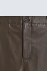 Pantalón de corte balloon fit confeccionado en piel, con bolsillos delanteros y traseros de vivo, cierre frontal con cremallera y botón.
