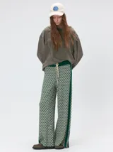 Pantalón de punto jacquard con diseño geométrico texturizado, de corte holgado y pierna ancha. Presenta tiro medio, cintura elástica con cordón ajustable y aberturas laterales en el ruedo.