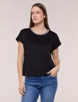 Blusa de silueta recta confeccionada en crepe elastizado, color negro, con escote a la base destacado con una delicada tira aplicada de perlas y cuentas, mangas cortas dollman y ruedo recto.