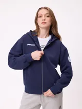 Canguro azul marino con cierre frontal, capucha y bolsillos laterales. Presenta un parche bordado con el número 85 en color celeste y blanco en la manga.