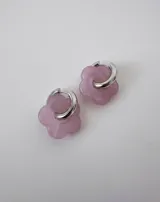 Aros de acero quirúrgico con argolla plateada y dije de flor translúcida en color lila con lunares negros.