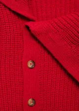Jersey de punto grueso color rojo, con cuello chimenea amplio y cierre frontal de botones. Presenta diseño recto y manga larga.