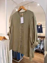Camisa de lino color verde militar, con cuello mao y cierre frontal de botones. Presenta un diseño de manga larga con puños arremangados y calce relajado.
