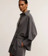 Camisa gris de tejido plano con corte sastre, cuello clásico, abotonada en el frente y puños largos.