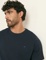 Remera básica de algodón color beige, de manga corta, con cuello redondo y un pequeño detalle bordado en el pecho.