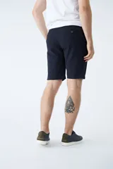 Bermuda tipo chino de gabardina color beige, con cierre de cremallera y botón, y diseño de cinco bolsillos.