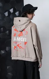 Hoodie oversize color gris topo, confeccionado en rústico de algodón, con capucha forrada, bolsillo canguro y costuras expuestas en mangas y ruedo. Presenta estampa gráfica en la espalda con la palabra AMOR y diversos motivos románticos.