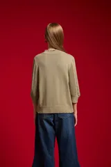 Sweater acrílico en tono natural, de corte holgado, con cuello a la base decorado con sutiles volados, mangas 3/4 y diseño tejido con motivos geométricos calados en el frente.