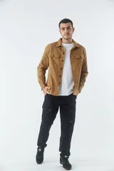 Sobrecamisa de jean color tostado, con cuello clásico, cierre frontal con botones y dos bolsillos frontales con solapa. Presenta mangas largas con puños abotonados y un pequeño parche decorativo en el ruedo.