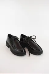 Zapatos tipo wallabee de cuero metalizado en tono peltre, con cordones negros y suela track de goma negra con plataforma.