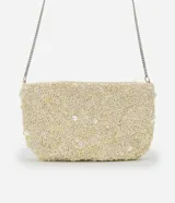 Cartera bandolera pequeña de forma rectangular, completamente cubierta de lentejuelas y cuentas brillantes en tono crema. Cuenta con cierre superior y una correa de cadena metálica plateada.