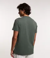 Remera verde militar de algodón, corte regular, cuello redondo y manga corta. Estampado frontal con un triángulo blanco que contiene una línea horizontal y una pequeña ola.