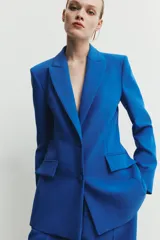 Blazer entallada de cuello solapa y manga larga con hombreras. Presenta bolsillos con solapa en el delantero, forro interior a contraste y cierre frontal con botones forrados.