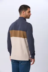 Remera polo de manga larga con diseño de bloques de color en azul marino, marrón y beige. Presenta cuello alto con cierre frontal parcial y estampa frontal con el logo de la marca.