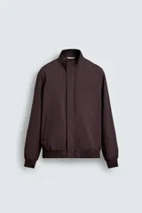 Cazadora de corte regular fit, color marrón oscuro, confeccionada en tejido técnico repelente al agua. Presenta cuello subido, manga larga, bolsillos de vivo en cadera, bolsillo interior y cierre frontal oculto por solapa con botones a presión.