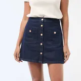 Falda corta de denim azul oscuro, con cierre frontal de botones metálicos dorados y dos bolsillos frontales tipo parche.