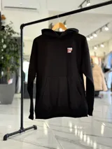 Canguro negro de corte oversize con capucha, manga larga y bolsillo tipo canguro al frente. En la espalda presenta un gran estampado gráfico con las palabras "Top Style" en blanco y rojo, acompañado de inscripciones y detalles minimalistas.