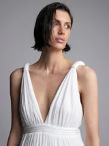 Mono largo blanco con escote en V, breteles finos con lazo y tajo lateral en la pierna.