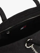 Cartera tipo tote de Tommy Jeans confeccionada en denim de algodón color negro. Presenta un diseño rectangular con asas superiores y una cadena metálica decorativa en el frente. Incluye el logo de la marca bordado en el centro.