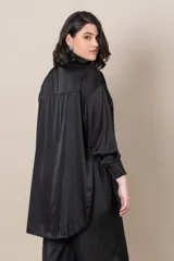 Camisa blanca oversize de satén italiano, con cuello clásico, cierre frontal con botones, mangas largas con puños anchos y tajos laterales.