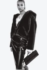 Pollera tubo de tiro alto confeccionada en tejido revestido con acabado efecto cuero. Presenta diseño de largo hasta la rodilla, bolsillos delanteros con cierre metálico y costuras verticales decorativas.