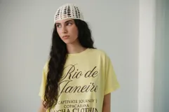 Remera amarilla de algodón con estampado frontal que incluye la frase 'Rio de Janeiro, a captivate journey, Copacabana, Icha Clothing since 2019'.