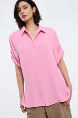 Camisa blanca de manga corta con puños doblados, cuello clásico y cierre frontal de botones.