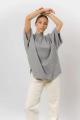 Sweater de tejido de punto color negro, con cuello semi alto y mangas cortas amplias. Presenta una silueta relajada y caída fluida.