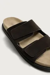 Sandalias de piel de acabado serraje en color marrón, con dos tiras anchas ajustables con cierre adherente en el empeine, plantilla anatómica y suela plana.
